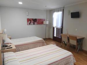 een hotelkamer met 2 bedden, een tafel en een bureau bij Hotel Santa Ana in Arrasate - Mondragon