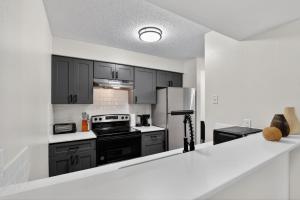 a kitchen with black cabinets and a refrigerator at Contemporary 2BR apartment with workspace in Lenexa