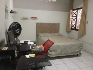 a bedroom with a bed and a desk with a computer at Férias pé na areia, sol e mar in Serra