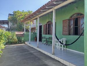 a green house with a porch with chairs on it at Férias pé na areia, sol e mar in Serra