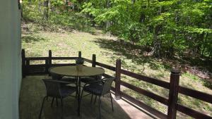 a table and chairs on a porch with a fence at Forest House Bukulja in Arandelovac