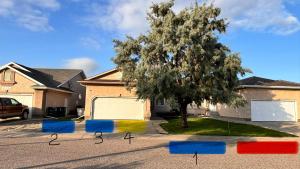 a house with a tree and colorful flags in a driveway at Saskatoon Lashyn Cove Homestay in Saskatoon