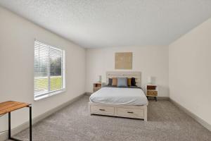 a white bedroom with a bed and a window at Spacious 2BR stay with updated interiors in Lenexa