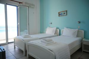 two beds in a room with a view of the ocean at Gigilos in Agia Roumeli