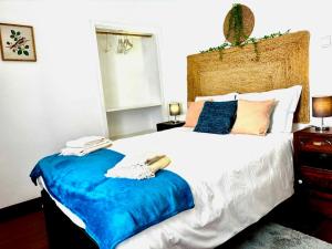 a bedroom with a large bed with a blue blanket at Casa Jardim 21 in Prazeres