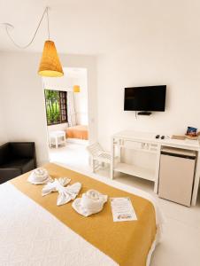 a white room with a bed with towels on it at Pousada Coisa e Tao in Arraial d'Ajuda
