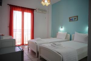 two beds in a room with blue walls and a window at Gigilos in Agia Roumeli