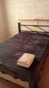 a bed with a black blanket and a towel on it at Pinkanta in Las Compuertas