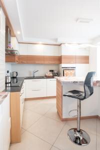 a kitchen with white cabinets and a bar stool at Casa vacanze Maria in Tesero