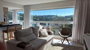 a living room with a couch and a large window at Apto Margaridas|3Q,todo Climatizado,ao lado Termas in Piratuba