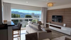 a living room with a white couch and a large window at Apto Margaridas|3Q,todo Climatizado,ao lado Termas in Piratuba