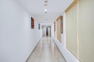 a long hallway with white walls and white tile floors at Palette A Lux Corporate Townhouse Near 3 Minutes Kaushambi Metro Station in Ghaziabad