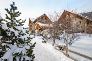 a log cabin in the snow with a fence at travelski home select - Résidence Les Chalets du Galibier 4 - 2 pièces 4 personnes in Valloire