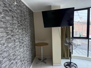 a living room with a tv on a brick wall at HOTEL CASA REAL Tacna in Tacna