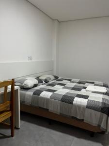 a bedroom with a bed with a black and white blanket at Apart Hotel Eucalyptus in Telêmaco Borba