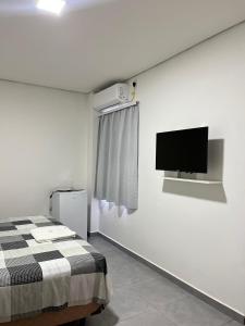 a bedroom with a bed and a tv on the wall at Apart Hotel Eucalyptus in Telêmaco Borba