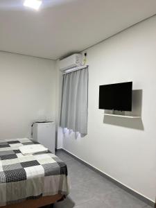 a bedroom with a bed and a tv on the wall at Apart Hotel Eucalyptus in Telêmaco Borba