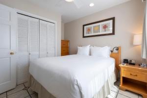 a bedroom with a large white bed and a nightstand at San Clemente Cove Resort in San Clemente