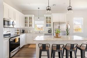 a kitchen with white cabinets and a island with bar stools at King Bed, Beach Views, The Salt Surf Shack in Bolivar Peninsula