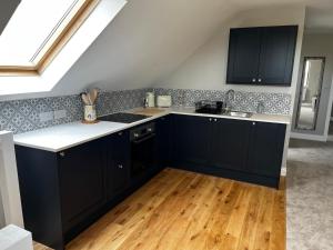 a kitchen with black cabinets and a wooden floor at The loft in Tingewick