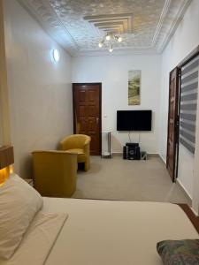 a bedroom with a bed and a tv and a chair at Chic Shop House in Abomey-Calavi