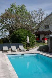 a swimming pool with two chairs and an umbrella at Maison chic avec Psicine - Talant proche Prenois in Talant