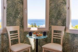 two chairs and a table with a plate of food and two windows at Blue Horizon Studio Opatija in Opatija
