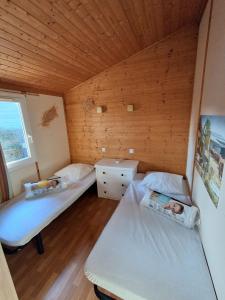 two beds in a room with a wooden ceiling at Chalet climatisé 6 personnes in Agde +27 photos