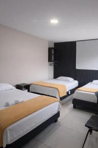 a hotel room with two beds and a screen at Hotel Escorial Ibagué in Ibagué