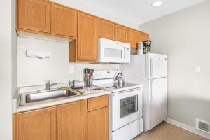 a kitchen with wooden cabinets and white appliances at Ocean view studio no stairs-Full Kitchen Patio in Lincoln City