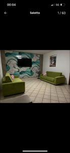 a living room with two green couches and a wall at Sogno vesuviano 4 in Torre del Greco