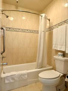 a bathroom with a toilet and a bathtub with a shower curtain at Castaic Inn Six Flags Valencia in Castaic