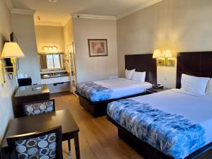 a hotel room with two beds and a table at Castaic Inn Six Flags Valencia in Castaic
