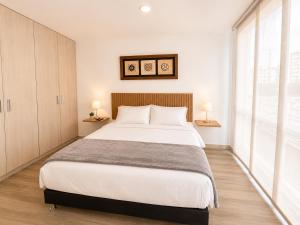 a bedroom with a large bed and a large window at Comodo Apto Diagonal MALL PLAZA in Manizales