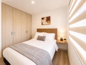 a bedroom with a large white bed and a window at Comodo Apto Diagonal MALL PLAZA in Manizales +21 photos