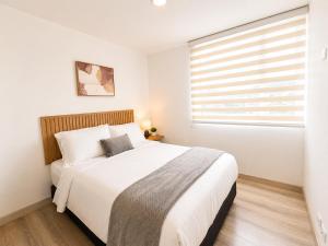 a white bedroom with a large bed and a window at Comodo Apto Diagonal MALL PLAZA in Manizales