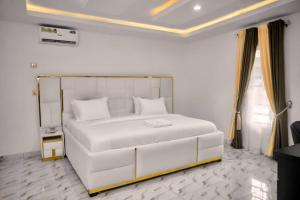 a bedroom with a large white bed in a room at BROOKLYN HoTEL in Benin City