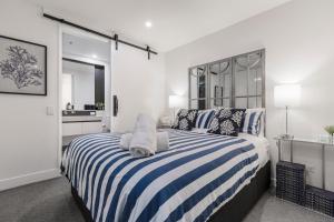 a bedroom with a large bed with blue and white stripes at The Port Melbourne Experience in Melbourne +20 photos