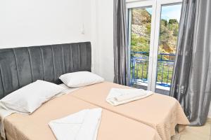 a bedroom with a bed and a large window at Ikaria Therma Blue in Agios Kirykos