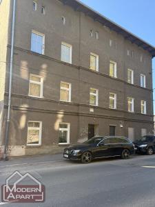 two cars parked in front of a brick building at Modern Apart in Wałbrzych