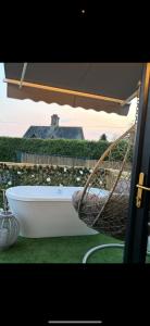 a white bath tub sitting under an umbrella at The Stallion in Sturminster Newton +1 photo