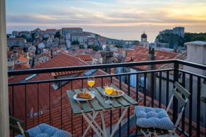 a table with two plates of food and drinks on a balcony at Whispering Views House Old Town in Dubrovnik