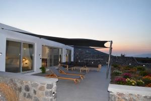 a patio with lounge chairs and an umbrella at Erimo Vip in Vourvoúlos