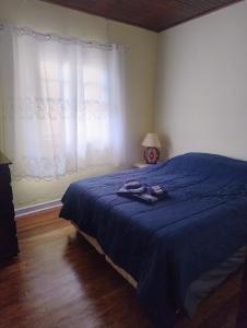 a bedroom with a bed with a blue blanket and a window at casa charme e praticidade in Campos do Jordão