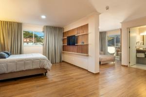 a bedroom with a bed and a living room at Pousada Sol da Mantiqueira in Campos do Jordão