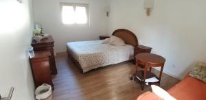 a bedroom with a bed and a table and a chair at Valérie GOUFFÉ Chambres d'hotes in Parigné-lʼÉvêque