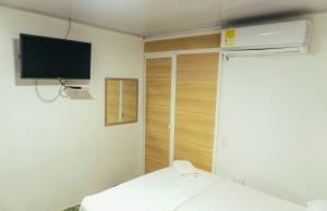 a room with a bed and a tv on the wall at VILLA SOL HABITACIONES in San Andrés