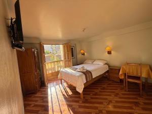 a bedroom with a bed and a table and a window at Nafis Casona Apu Linli Pisac in Pisac