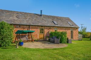 a brick cottage with a patio and a swing at 1 Bed in Broadway oc-36842 in Broadway