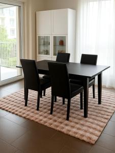 a black dining room table and chairs on a rug at PepinA'S Home in Martigny-Ville